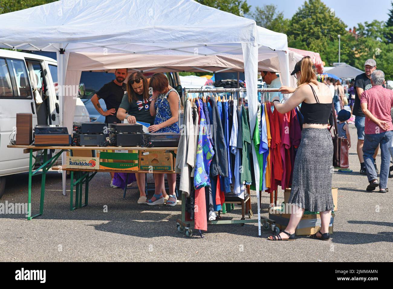 Heidelberg, Germania - Agosto 2022: Donna che guarda attraverso il rack con vecchi vestiti di seconda mano al mercato delle pulci Foto Stock