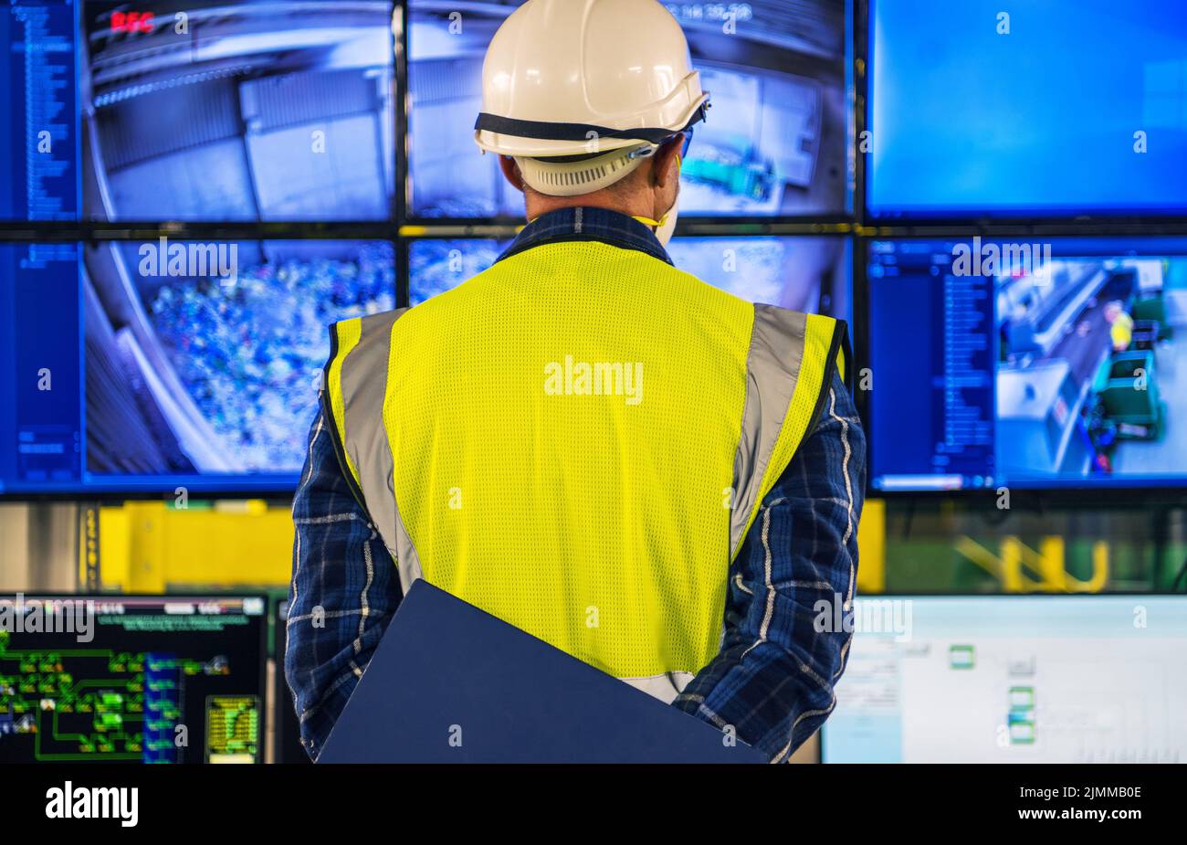 Il tecnico caucasico che si trova di fronte alla sala di controllo della struttura visualizza il controllo di tutti i processi tecnologici. Foto Stock