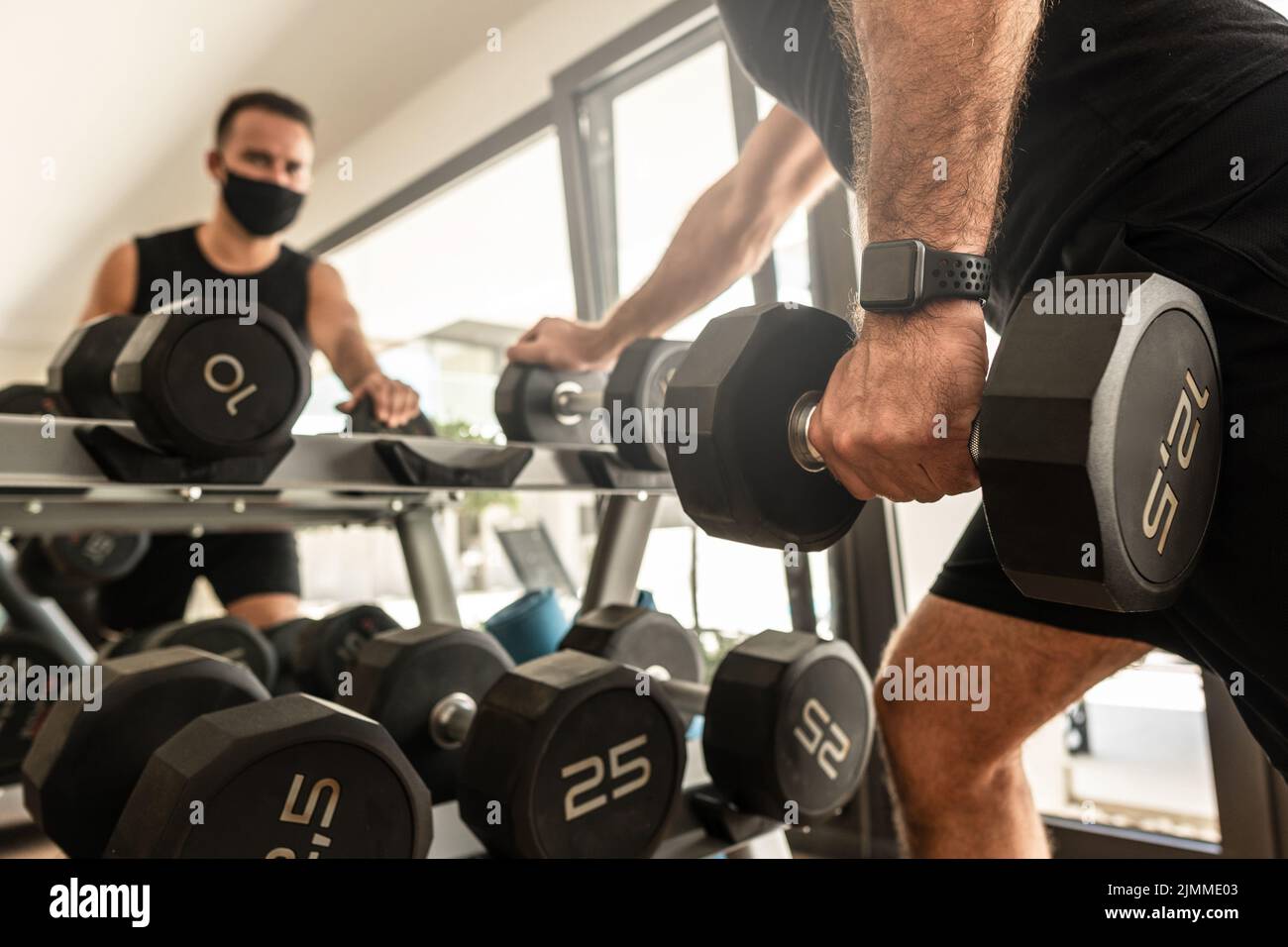 Giovane atletico che indossa una maschera facciale di prevenzione durante il suo allenamento in palestra Foto Stock