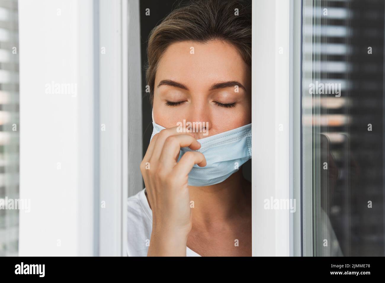 Donna sta andando su un balcone per prendere un respiro profondo perché stava usando la maschera di prevenzione Foto Stock
