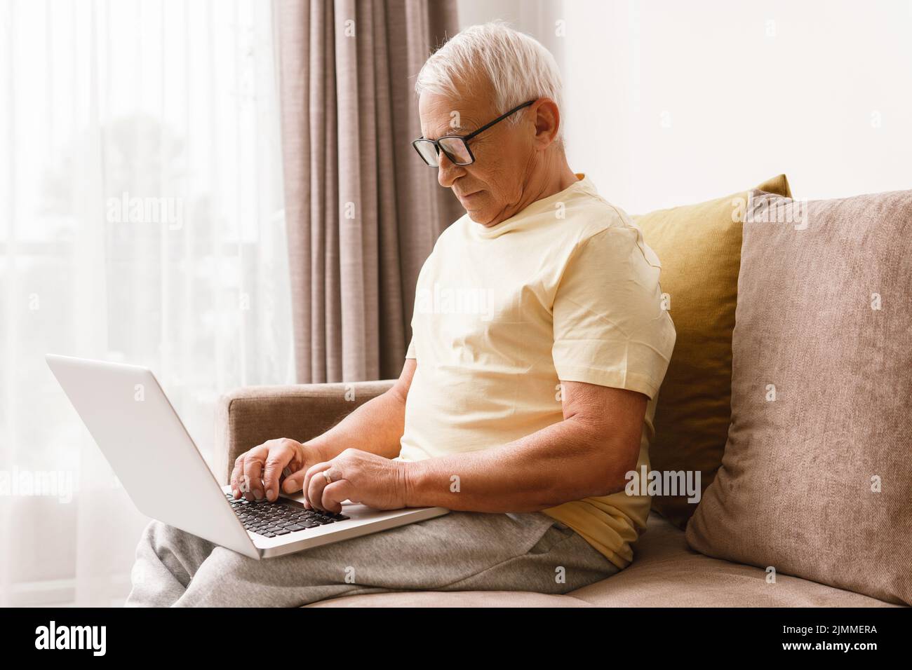 L'uomo anziano utilizza un computer portatile a casa Foto Stock