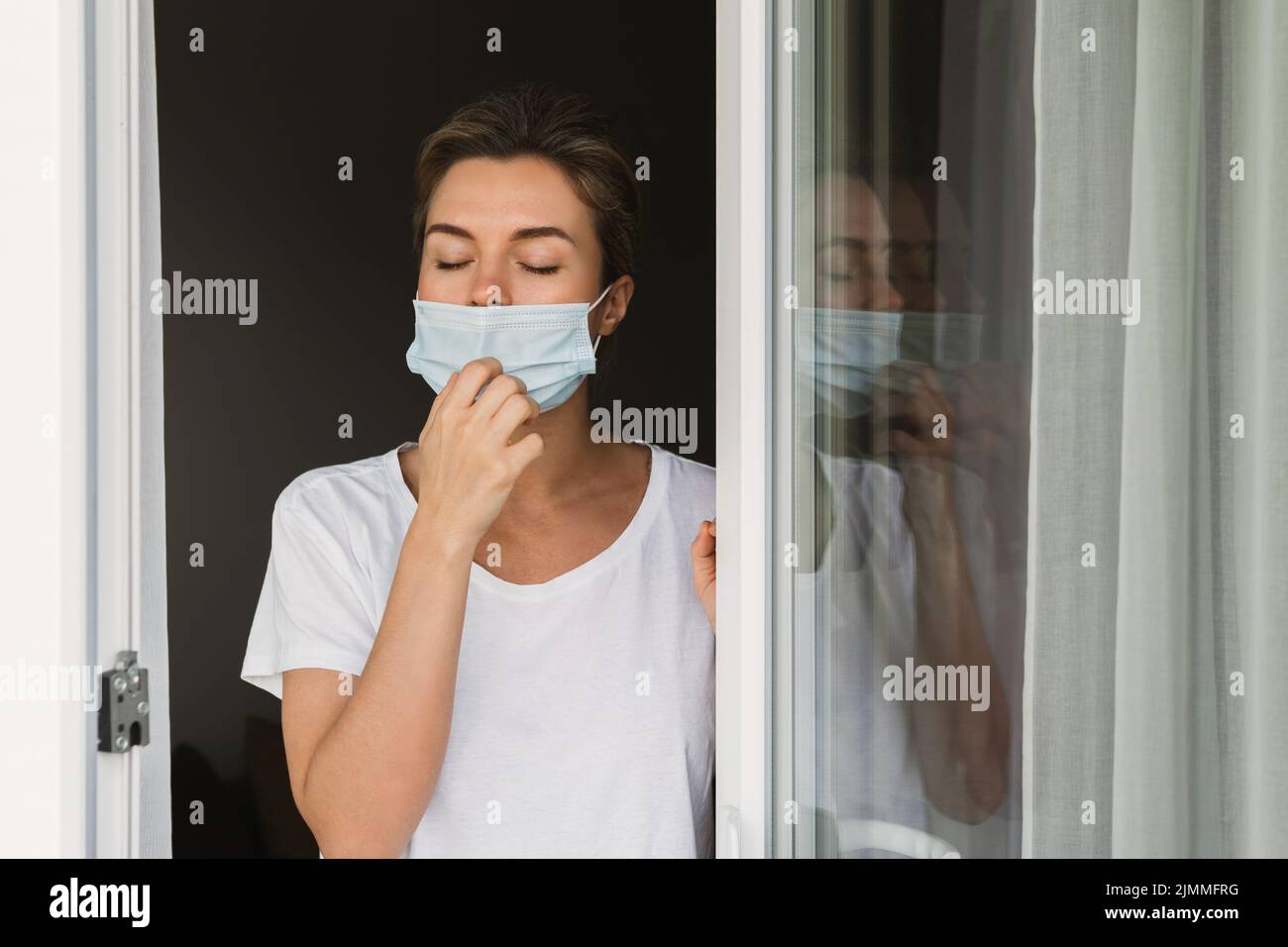 Donna sta andando su un balcone per prendere un respiro profondo perché stava usando la maschera di prevenzione Foto Stock