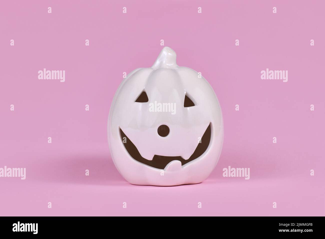 Decorazioni in pelle di zucca singola con faccia su sfondo rosa Foto Stock