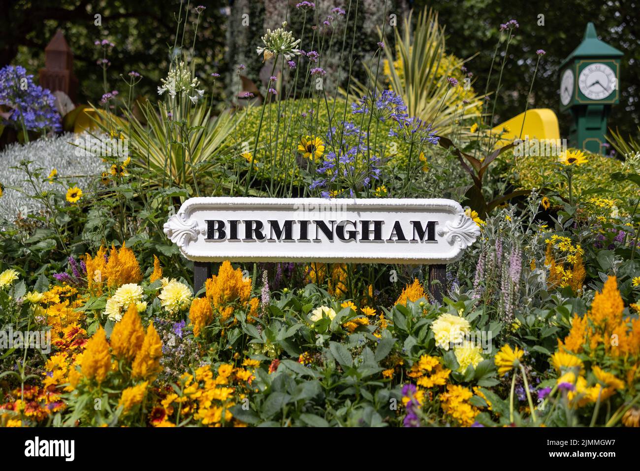 Cartello della città di Birmingham circondato da fiori nel giardino del parco del centro città. Vecchio testo nero su cartellonistica metallica su sfondo bianco. Foto Stock