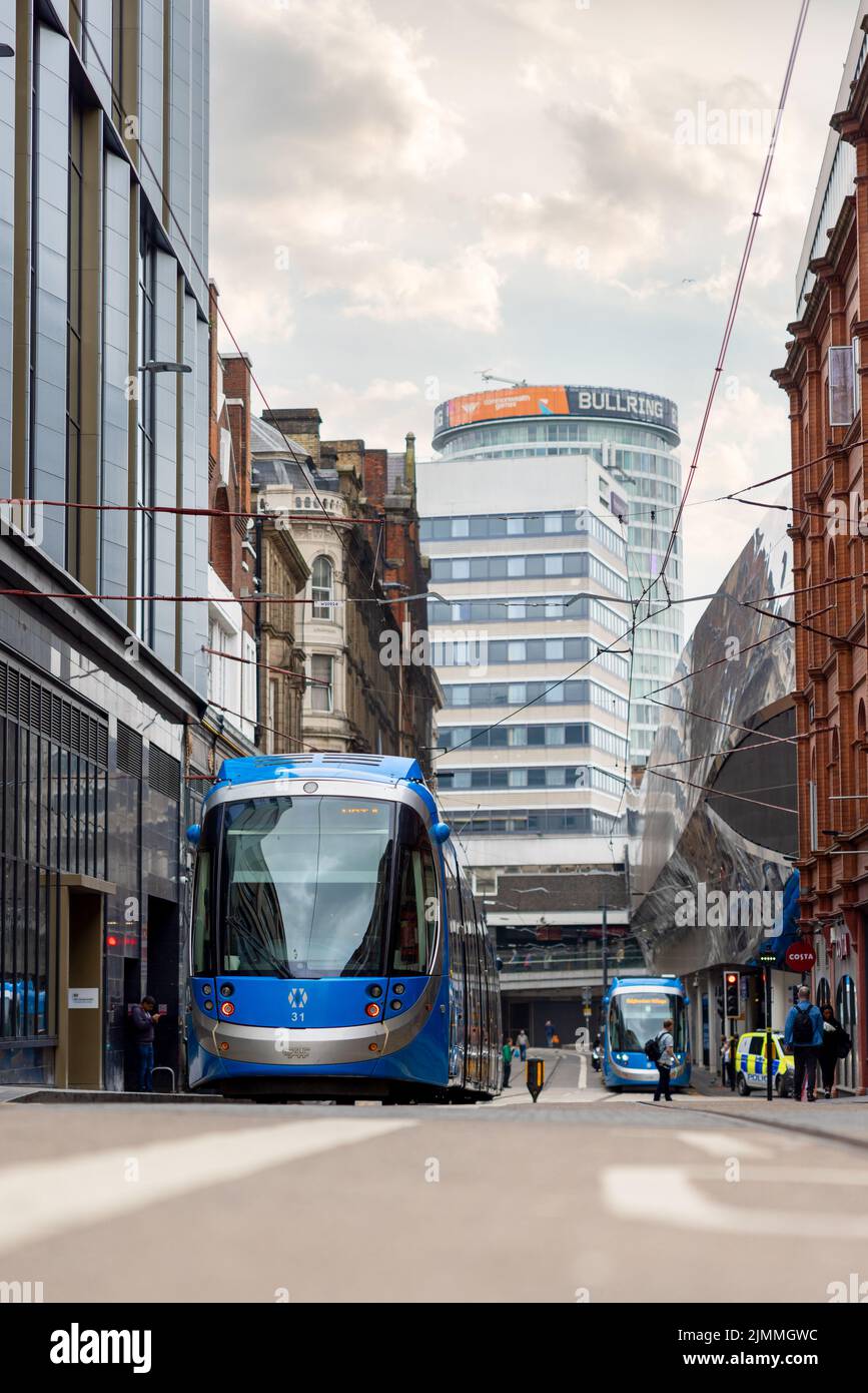 Stazione ferroviaria di Birmingham UK. Moderno tram urbano blu che attraversa il centro della città passando per i vecchi edifici. Foto Stock