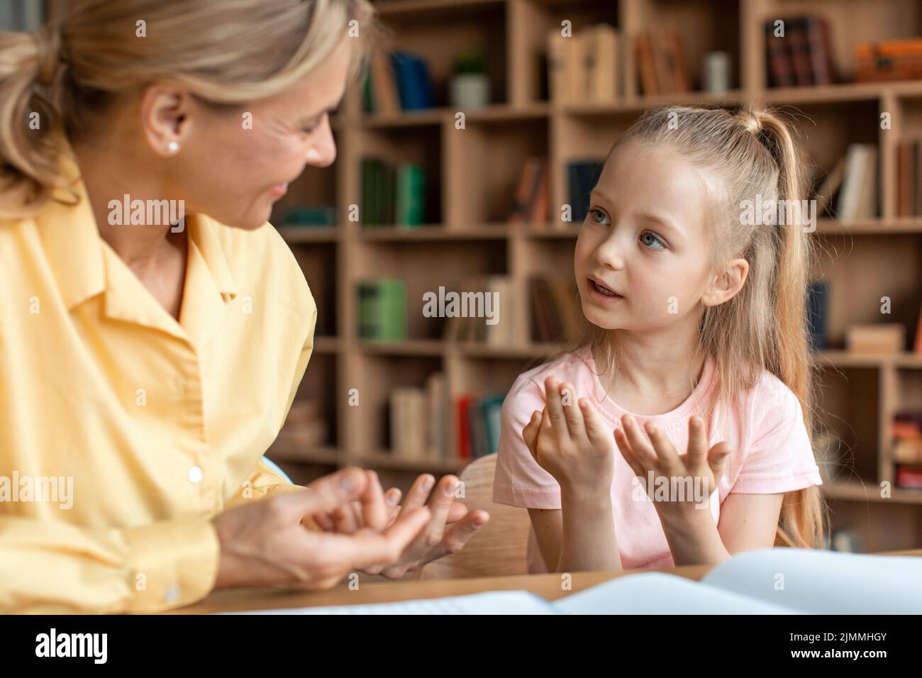 Ragazza caucasica intelligente preschooler che ha learing per contare con la sua madre che aiuta, seduta alla scrivania in soggiorno e studiare Foto Stock
