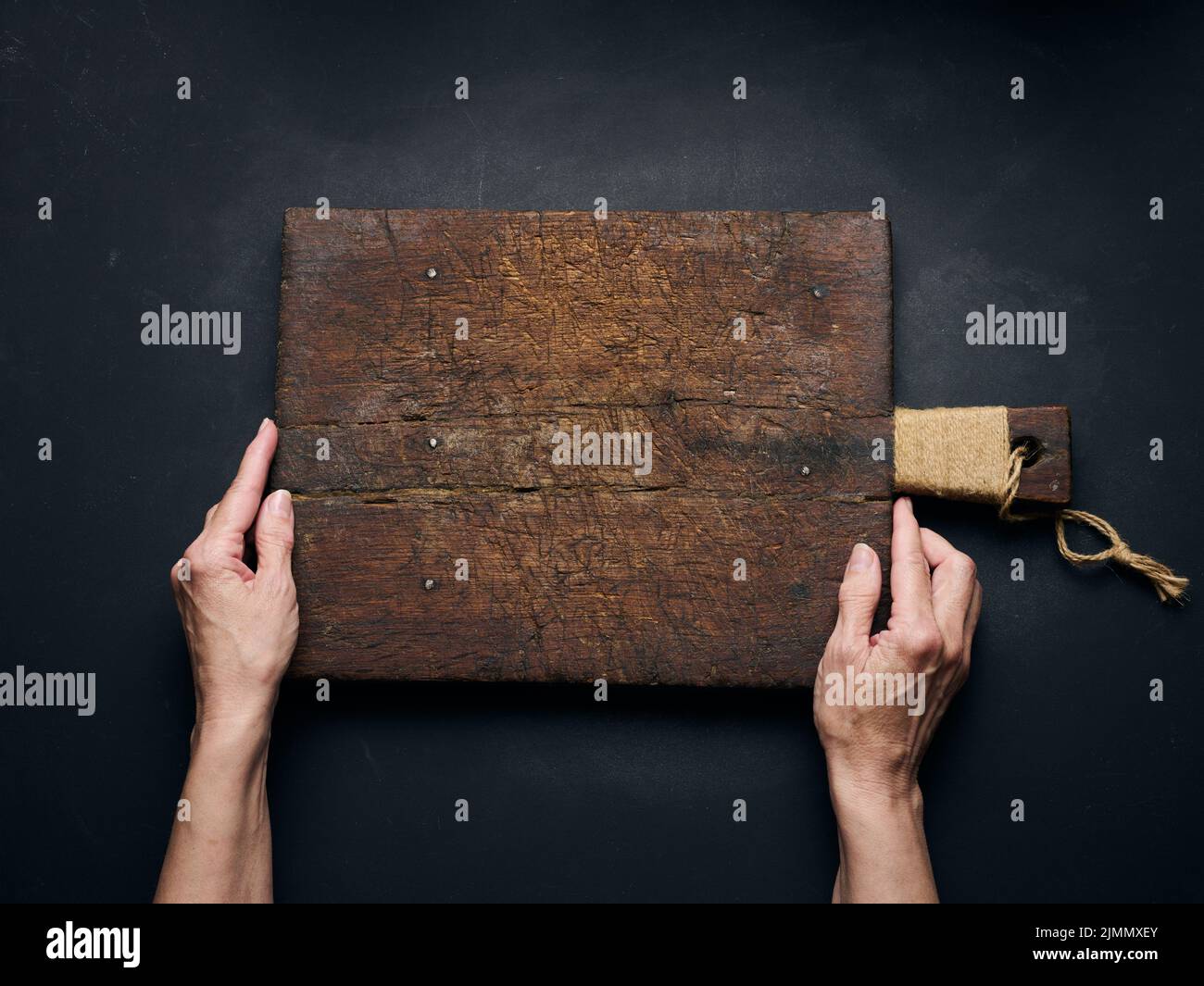 Tagliere in legno vuoto a mano femmina su tavola in legno nero, vista dall'alto Foto Stock