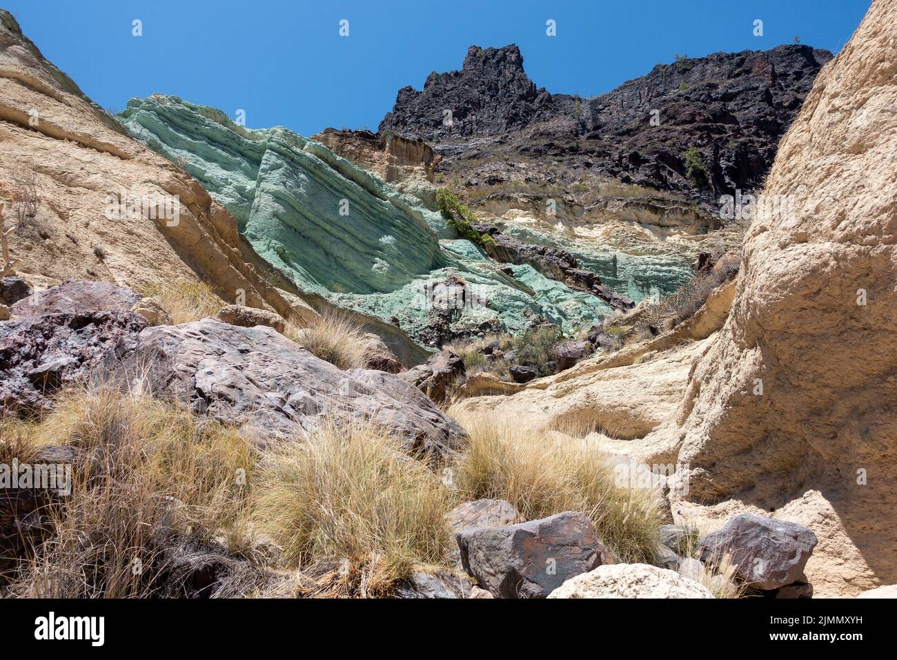 Turchesi strato di roccia los Azulejos De Veneguera, roccia vulcanica intrisa di sodio silicato di ferro, a Mogan, lampreda di erba Foto Stock