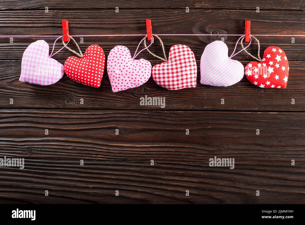 Cuori di San Valentino appesi su corda su sfondo di legno scuro Foto Stock
