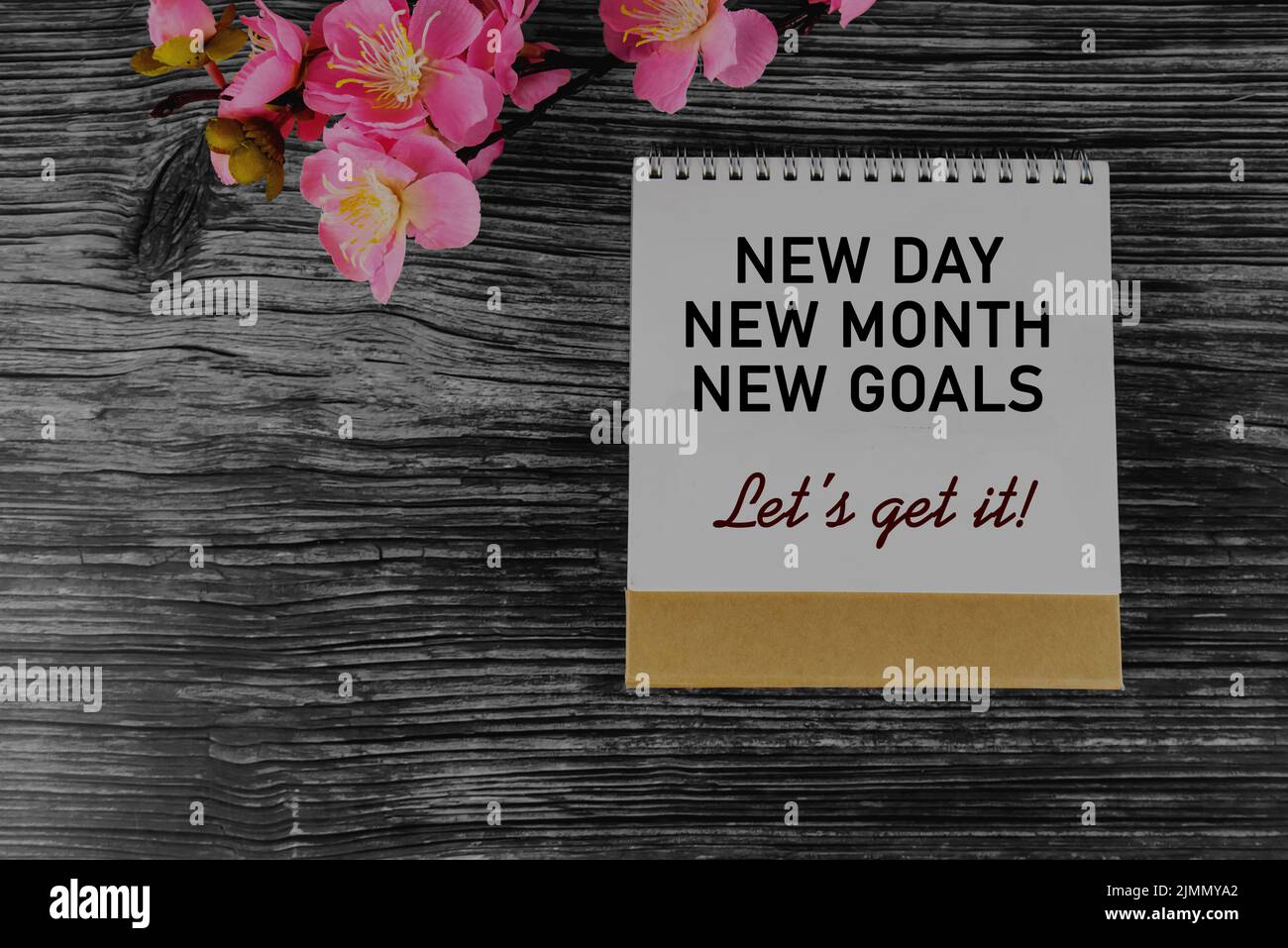 Messaggio positivo di motivazione aziendale sulla pagina di copertina del calendario - nuovo giorno, nuovo mese, nuovi obiettivi. Otteniamo. Con decorazione floreale rosa sul tavolo. Foto Stock