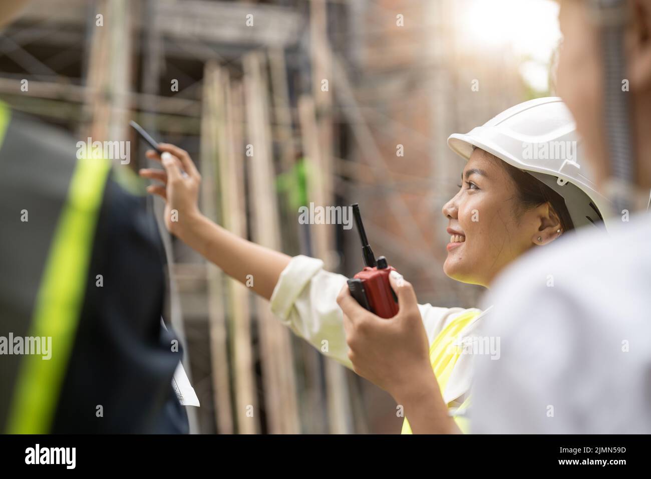 Ingegnere femminile asiatico che utilizza il lavoro di ordinazione radio presso il cantiere di costruzione Foto Stock