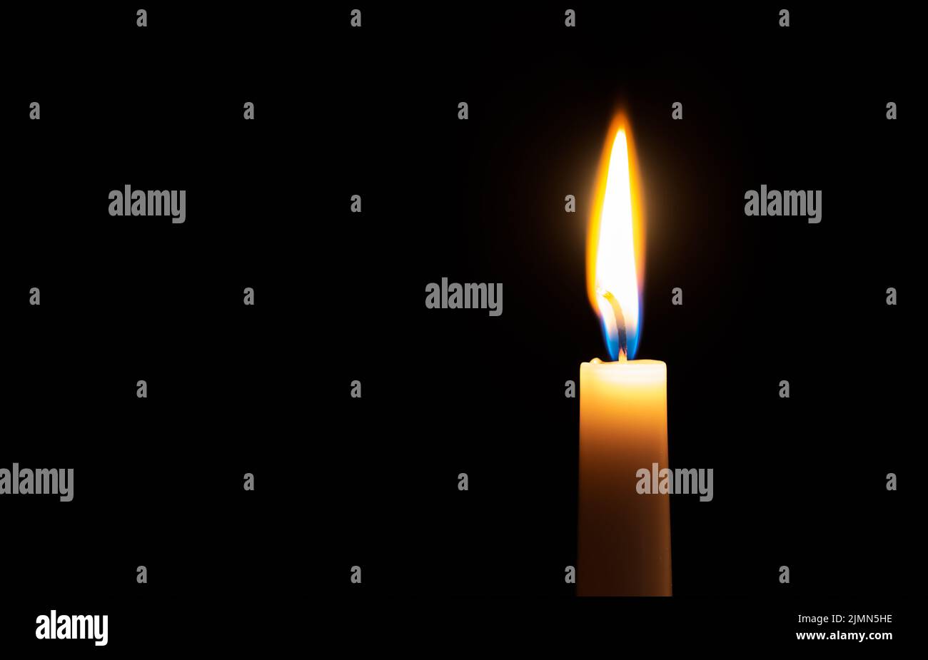 Candela singola illuminata con fiamma su sfondo nero Foto Stock