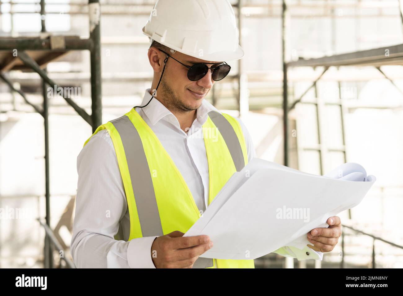 Uomo architetto indossare giubbotto di sicurezza con un progetto su un cantiere Foto Stock