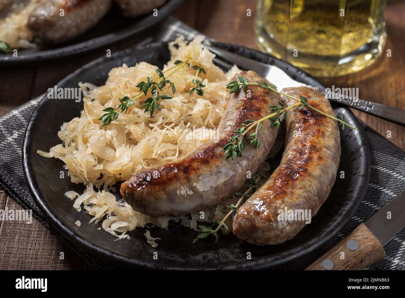 Bratwurst alla griglia e crauti guarniti con timo su un piatto nero Foto Stock