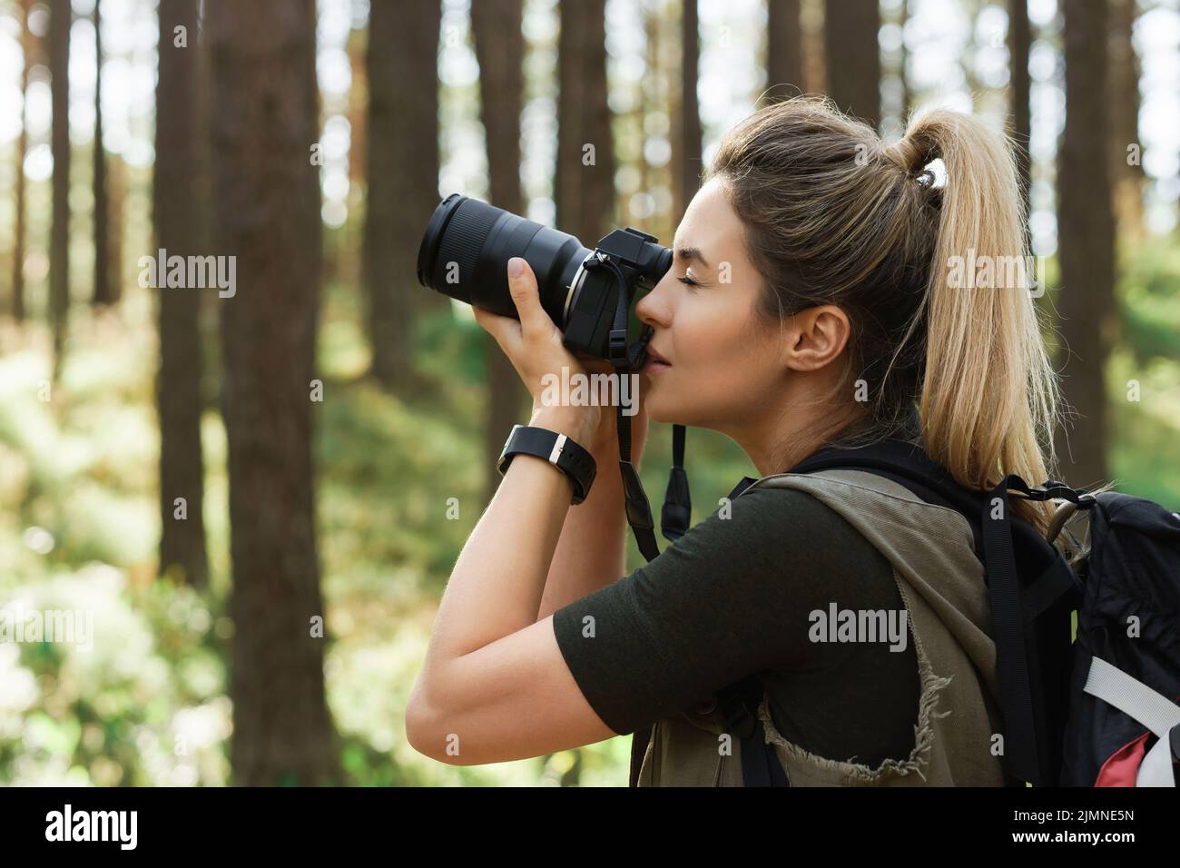 L'escursionista scatta foto utilizzando una moderna fotocamera mirrorless nella foresta verde Foto Stock