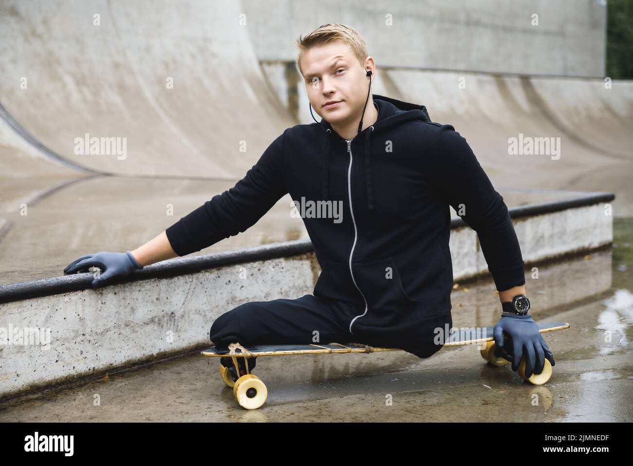 Giovane disabile con un longboard in uno skatepark Foto Stock