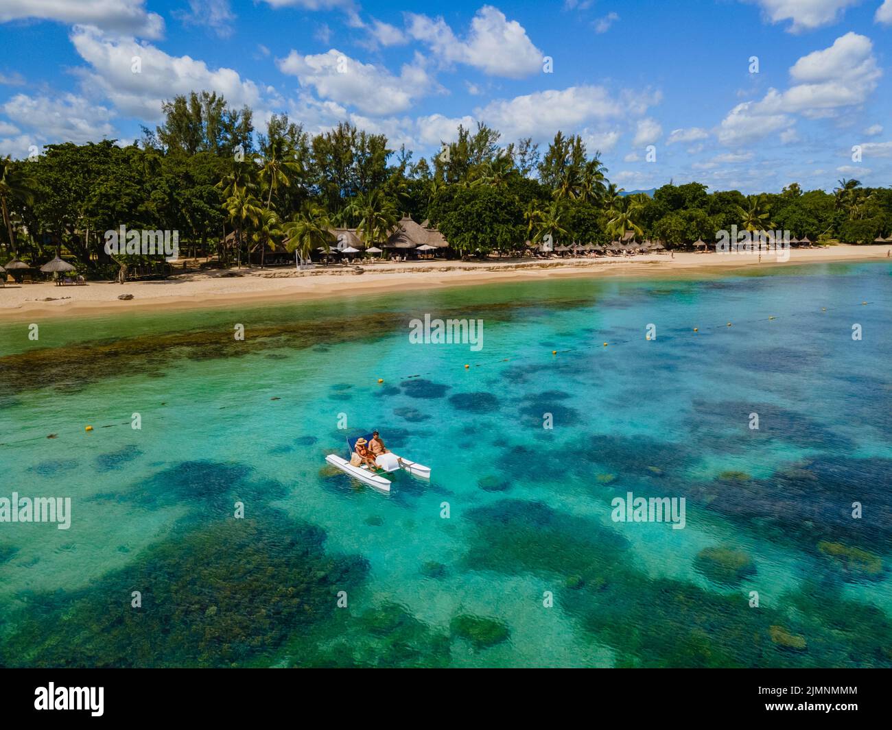 Pedalò e pedalò sull'idilliaca spiaggia orlata di palme, coppia uomini e donne in vacanza Mauritius Foto Stock