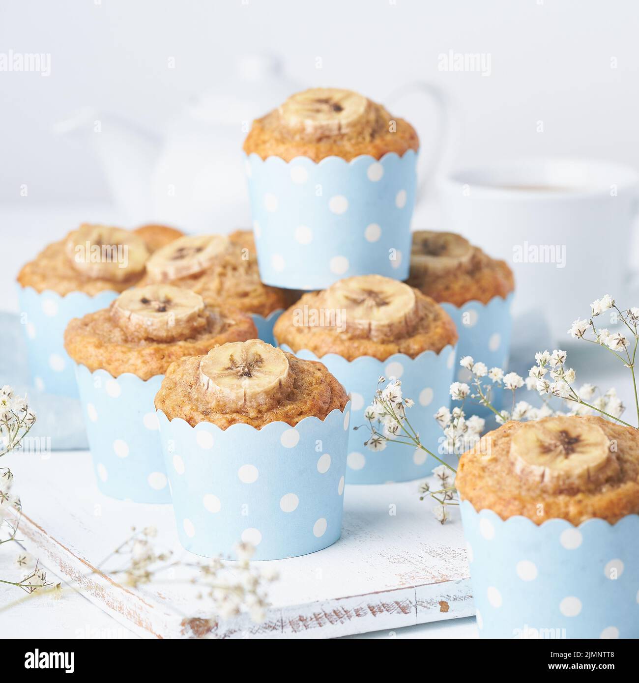 Muffin banana, cupcake in carta blu per dolci, vista laterale. Colazione al mattino su bianco Foto Stock