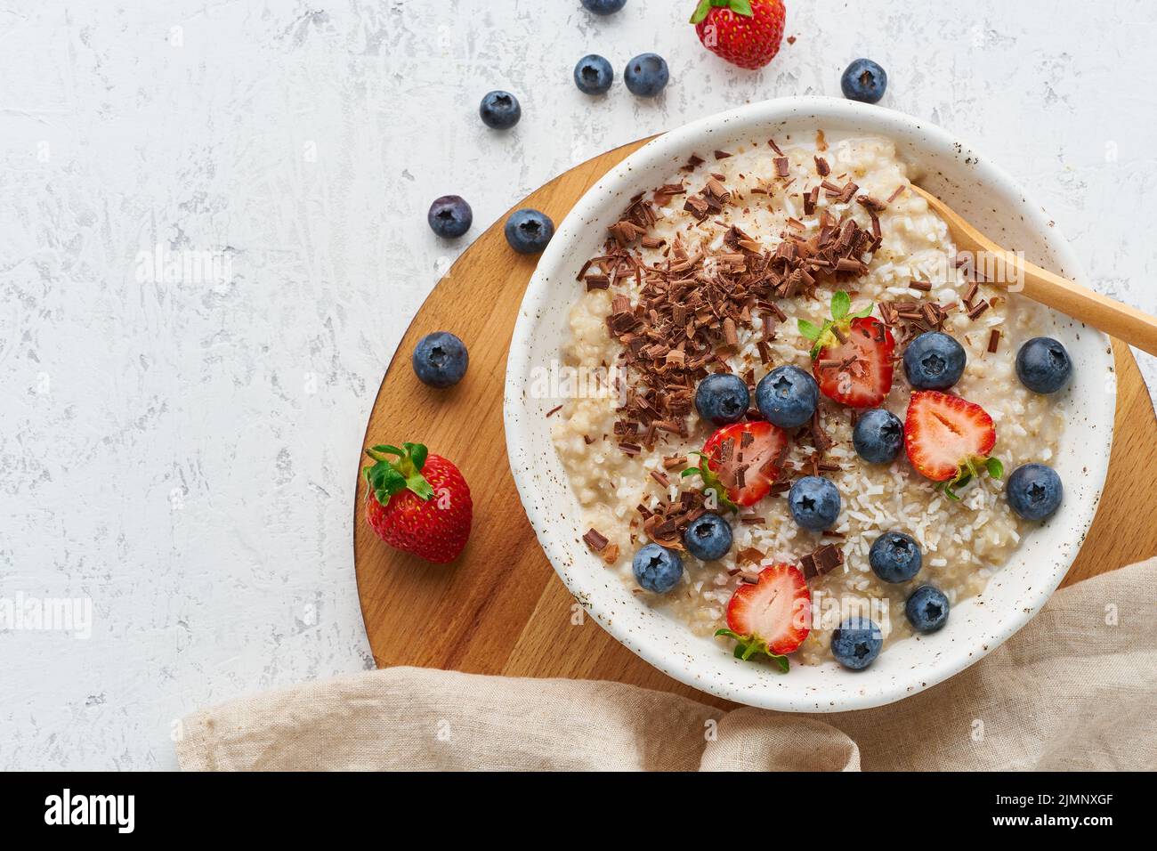 Porridge d'avena rustico con frutti di bosco e cioccolato, dieta a dash, su sfondo bianco vista dall'alto Foto Stock