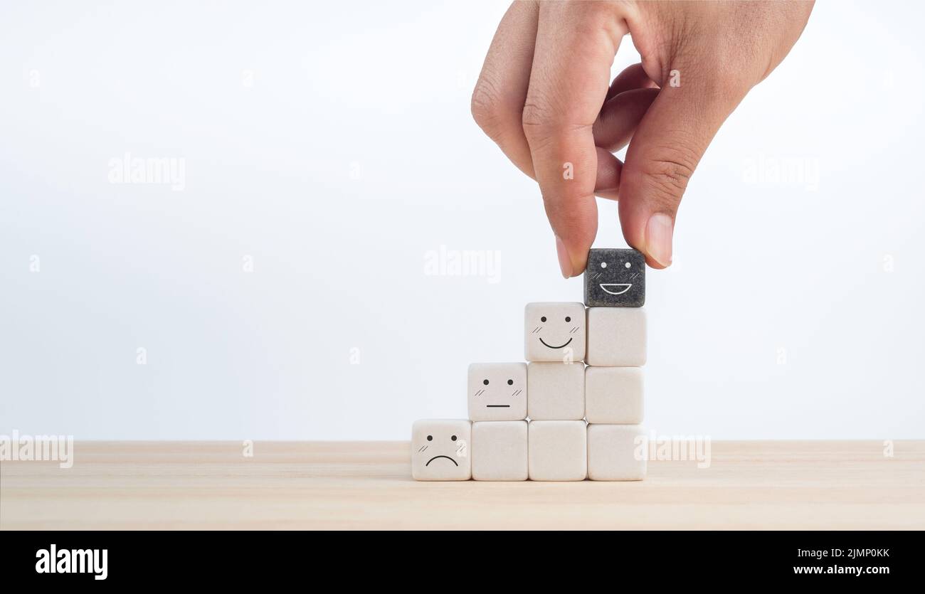 Feedback, sondaggio cliente, scala di valutazione soddisfazione esperienza cliente con faccia emoticon. Mano mettere il sorriso felice faccia sul cubo nero sulla parte superiore di w Foto Stock