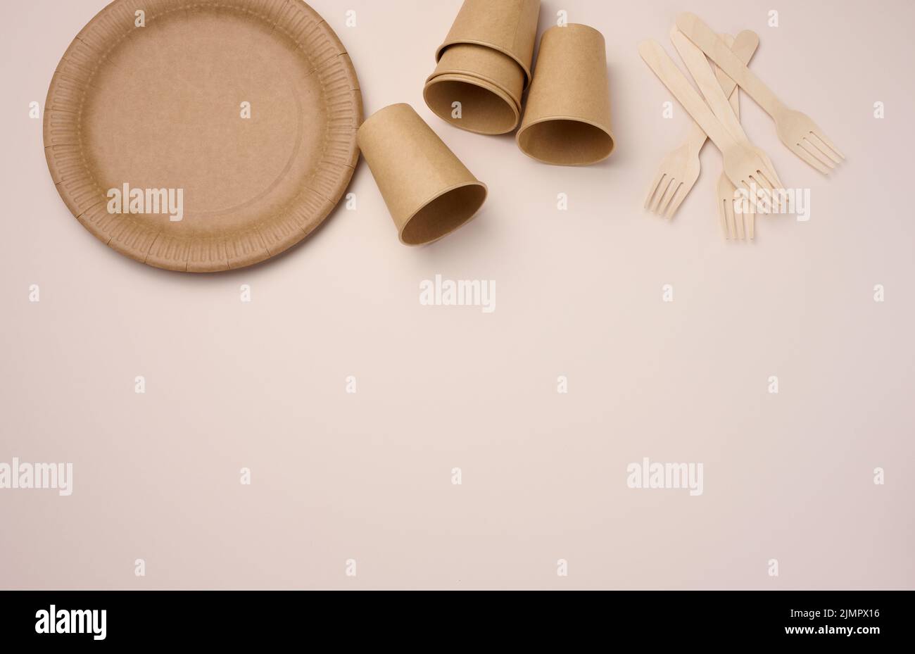 Tazze e piatti di carta marroni su sfondo beige. Rifiuti riciclabili, rifiuto di plastica, vista dall'alto Foto Stock