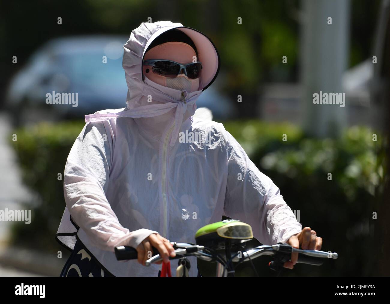 Fuyang, Cina. 07th ago 2022. Una donna va in bicicletta indossando un cappello, una maschera e occhiali da sole durante il tempo caldo. Secondo le previsioni dell'Osservatorio Meteorologico Centrale della Cina, nei prossimi 10 giorni, le alte temperature continueranno in alcune parti della Cina, con la temperatura massima che raggiunge i 37-39 ° C e la temperatura locale di 40 ° C o superiore. Credit: SOPA Images Limited/Alamy Live News Foto Stock