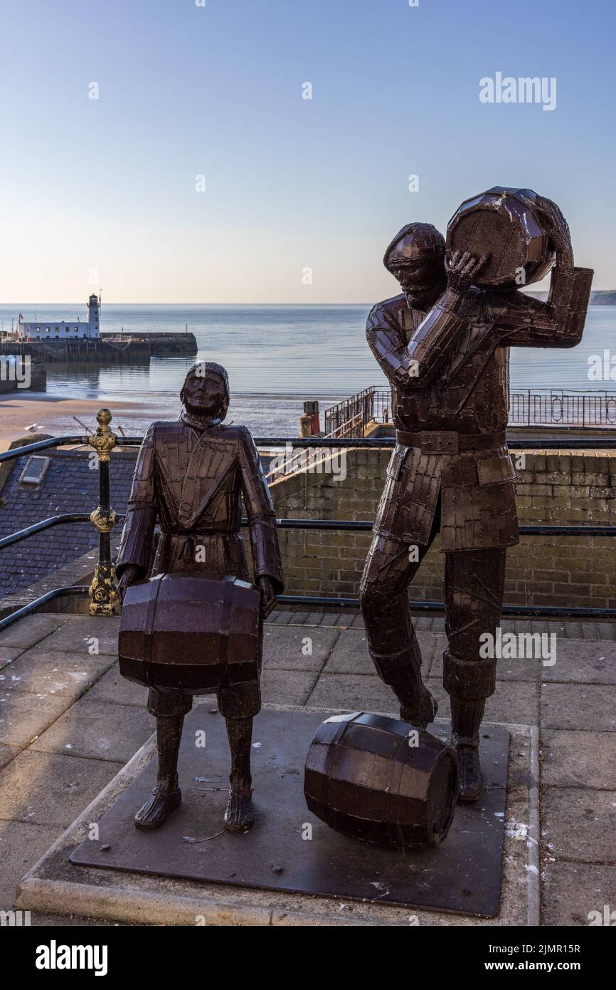 The Smugglers Apprentice, una scultura in acciaio di un uomo e di un ragazzo che porta barili, dell'artista Ray Lonsdale a Merchants Row a Scarborough, Yorkshire. Foto Stock