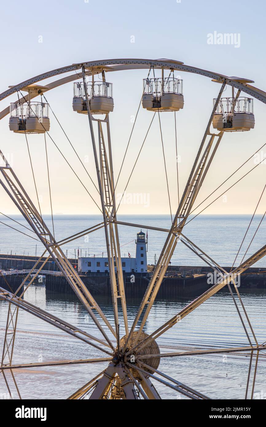 Una vista del faro del porto e del molo attraverso la Big Wheel sulla South Bay di Scarborough, sulla costa settentrionale dello Yorkshire. Foto Stock