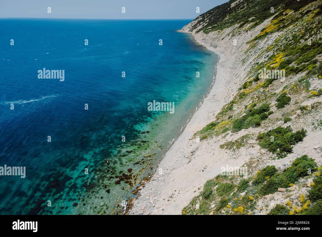 Vista aerea della costa con mare trasparente e scogliera. Giorno d'estate su un mare blu tranquillo Foto Stock