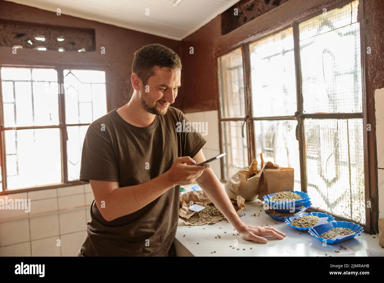 Uomo felice che guarda lo schermo dello smartphone in una fattoria di caffè in Africa Foto Stock