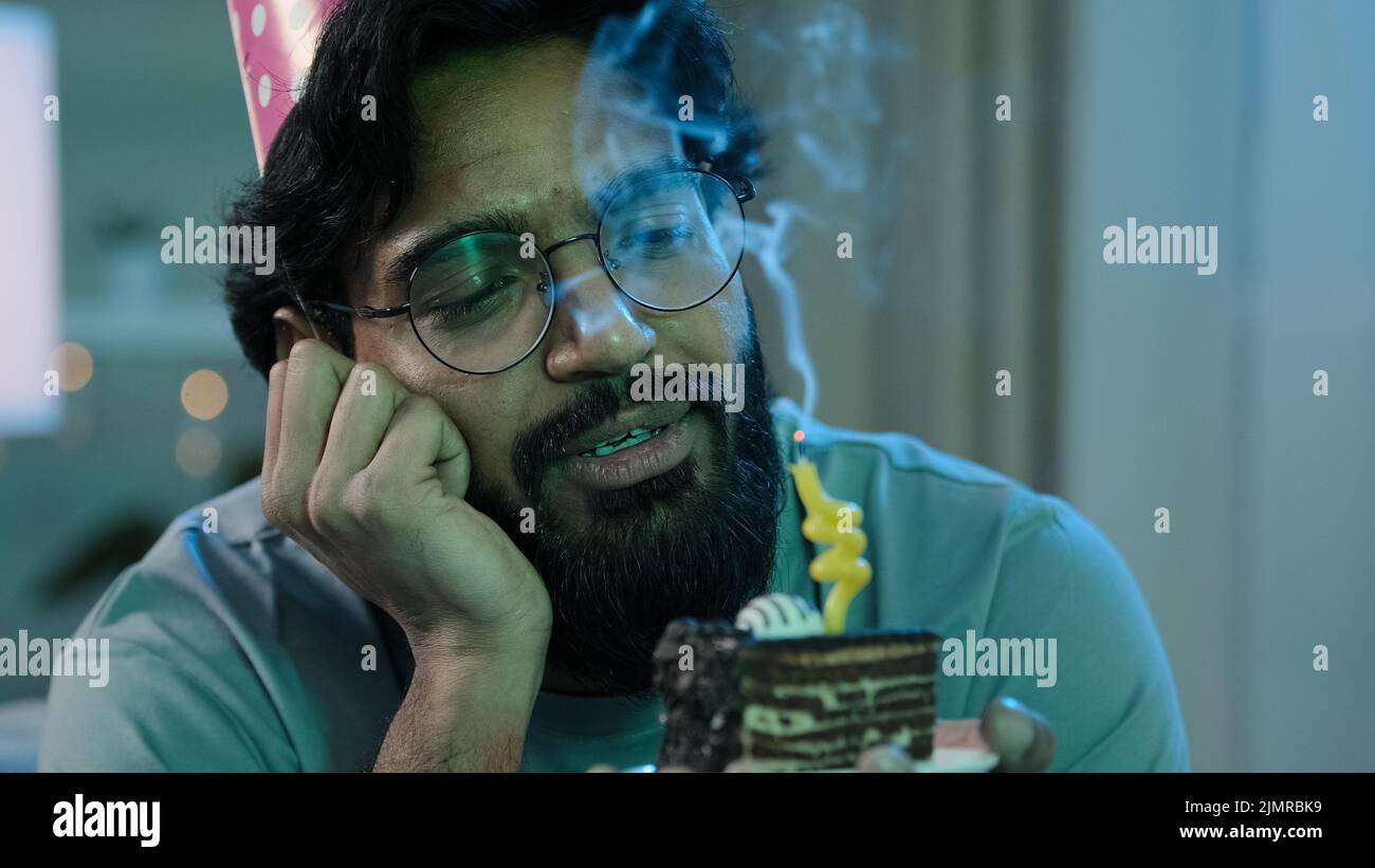 Headshot arabian da solo singolo triste sconvolto da solo uomo in berretto rosa di compleanno e bicchieri seduti a casa di notte sentire frustrata disperazione Foto Stock