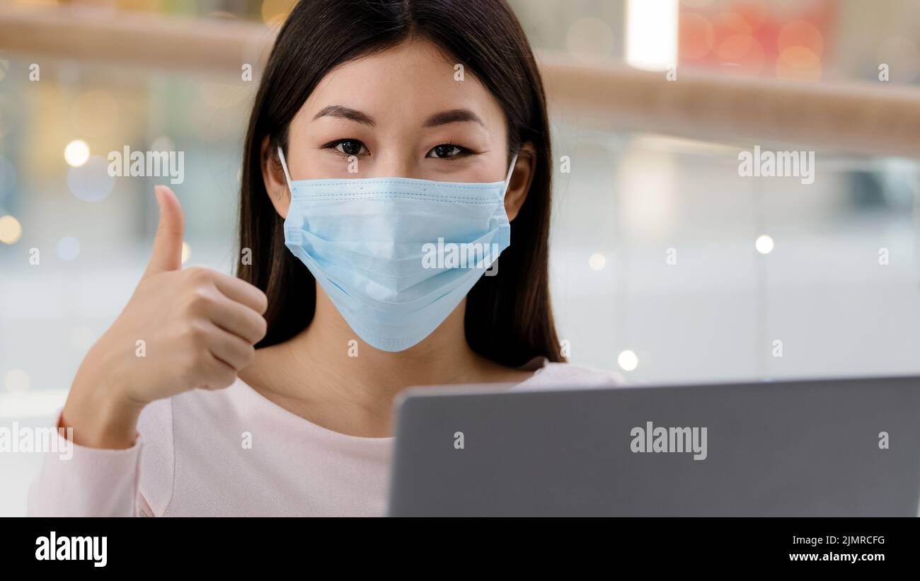 Asiatico coreano successo soddisfatto business donna lavoratore freelancer studente ragazza designer specialista in faccia maschera medica con laptop guardando la fotocamera Foto Stock