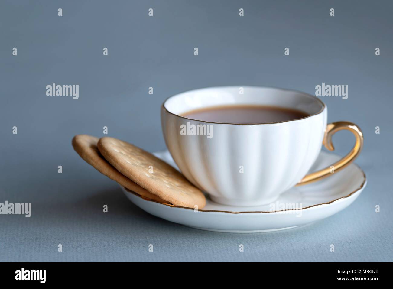 Una tazza forte di tè inglese tradizionale, con latte e due ricchi biscotti al tè. Servito in una classica tazza di porcellana di ossa e piattino. Una bella birra rinfrescante Foto Stock