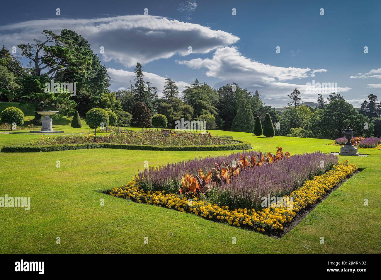 Powerscourt giardino con aiuole, siepi, alberi decorativi, fontane e la foresta sullo sfondo, Irlanda Foto Stock