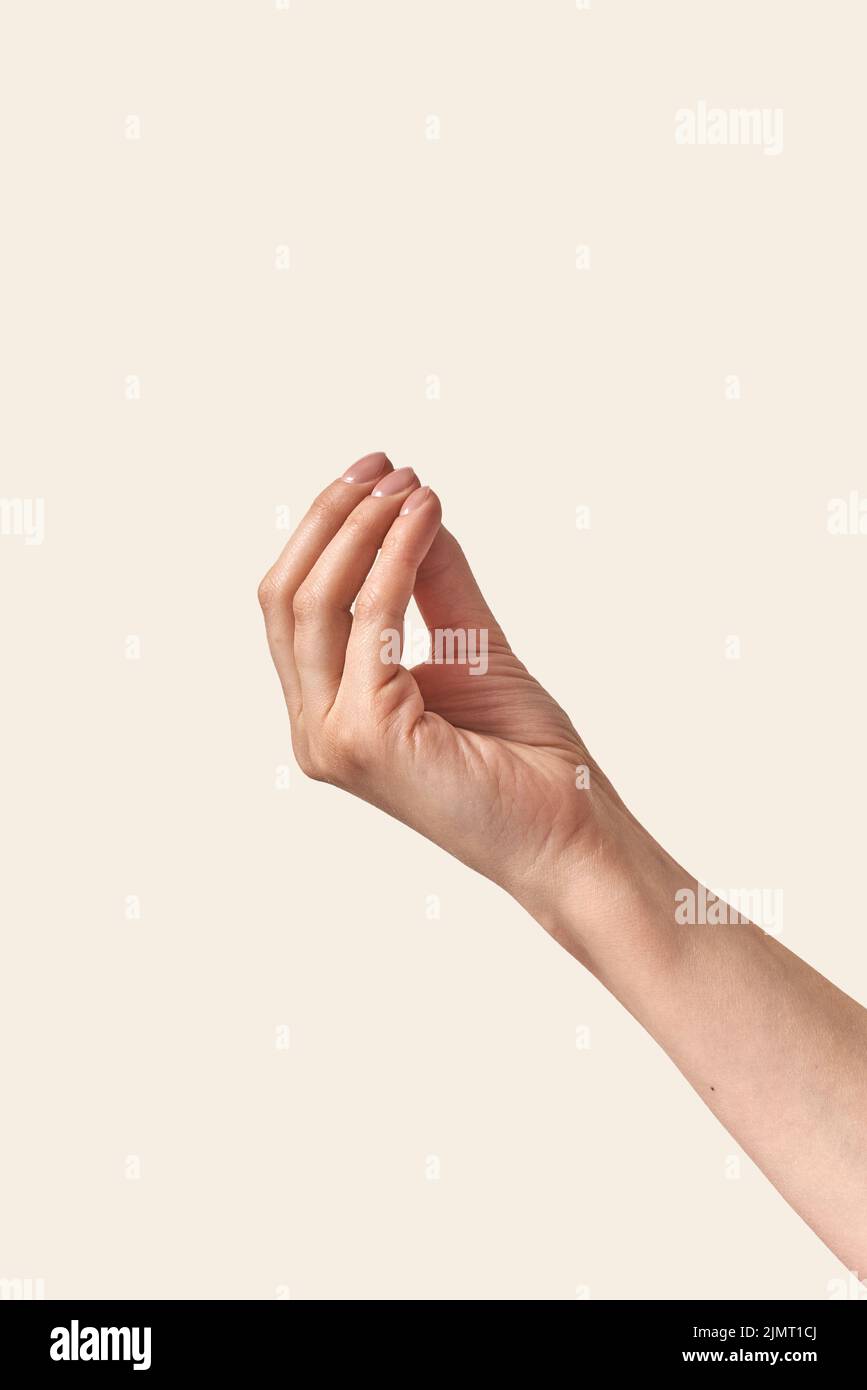 Oggetto invisibile che tiene la mano femminile su sfondo crema. Foto Stock