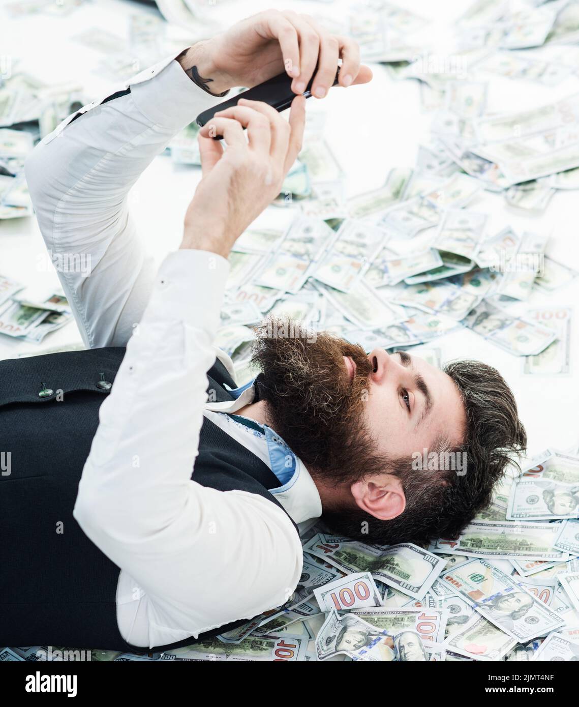 Uomo d'affari. Uomo bearded con il telefono che giace sulle banconote. Finanza. Successo aziendale. Pagamento online. Foto Stock