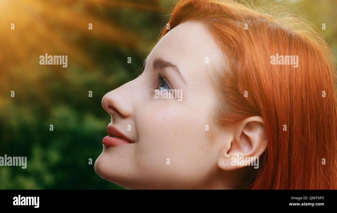 Primo piano femmina ispirato grazioso profilo faccia attraente modello adolescente bella redhead ragazza si alza fuori raggi di sole tramonto sfondo giovane sognante Foto Stock