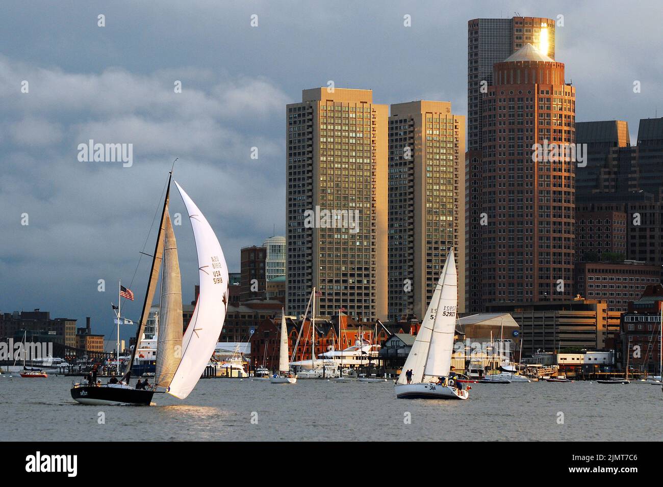 Una regata di barche a vela scivola oltre il Boston Skyline e attraverso il porto di Boston in una calda giornata estiva soleggiata Foto Stock