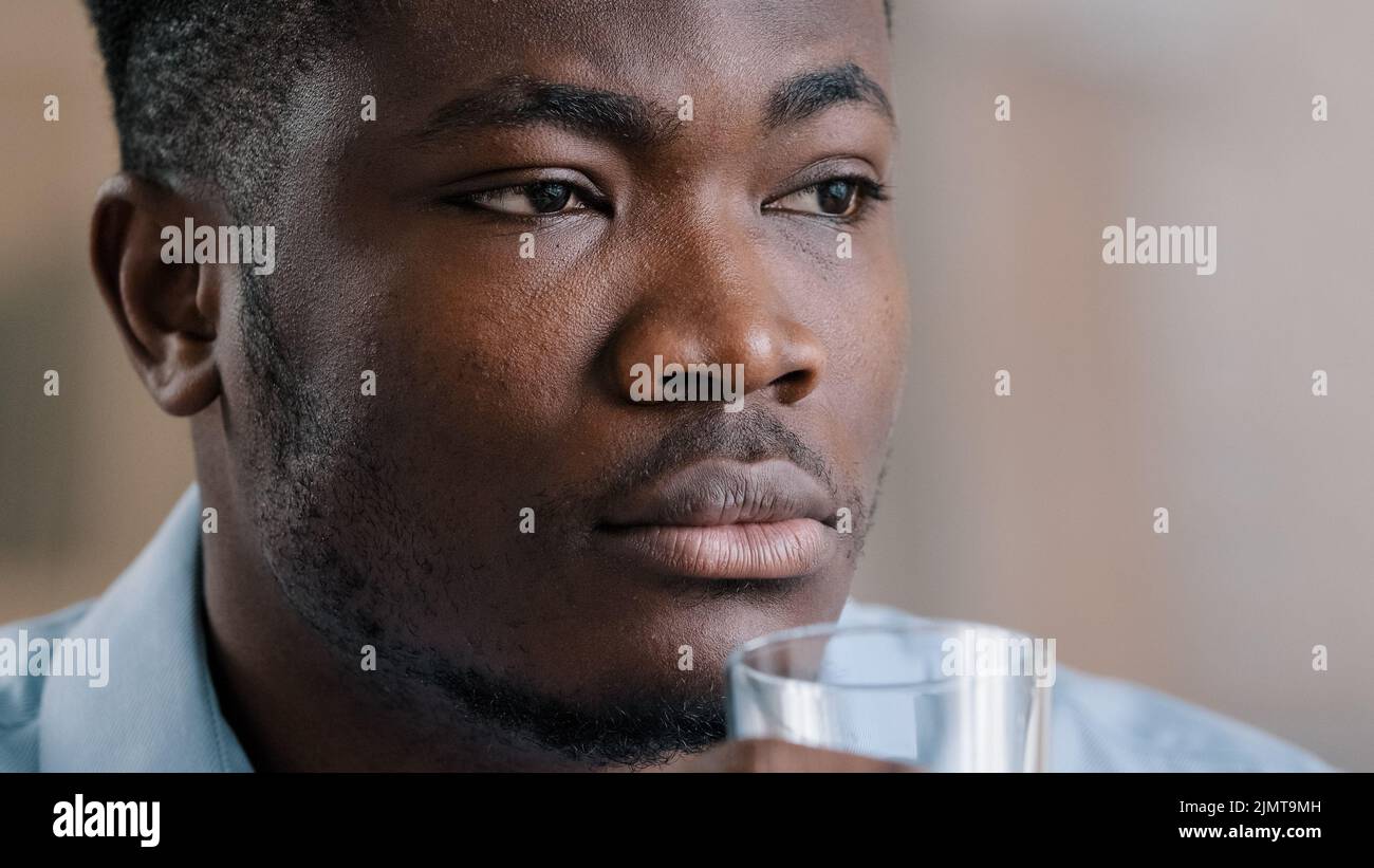 Primo piano Headshot african millennial man drink puro fresco acqua fredda vetro sano liquido soffre di caldo fare l'abitudine quotidiana idrato sete americana tho Foto Stock
