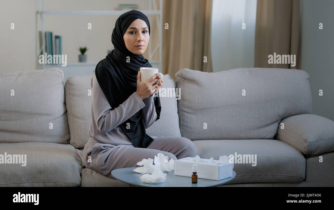 Malata musulmana araba giovane donna malsana in hijab soffre di malattia di influenza naso che cola allergia stagionale starnuti soffiare naso in carta tovagliolo sintomi di Foto Stock