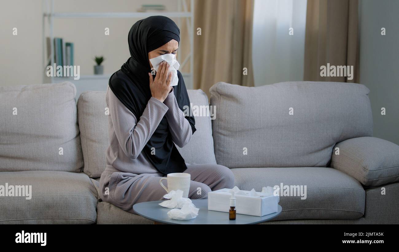 Malata musulmana araba giovane donna malsana in hijab soffre di malattia di influenza naso che cola allergia stagionale starnuti soffiare naso in carta tovagliolo sintomi di Foto Stock