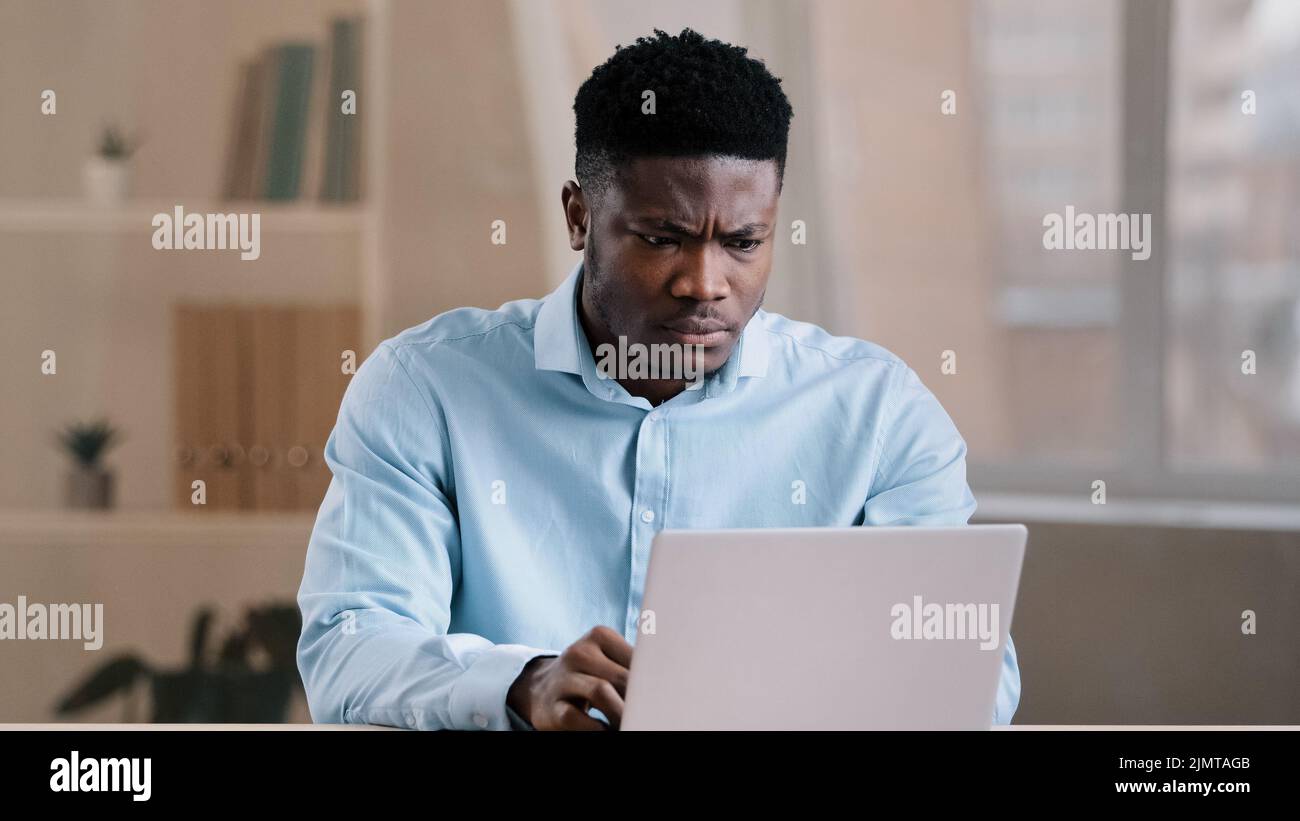 Ragazzo arrabbiato infastidito uomo africano americano capo lavoratore insoddisfatto ha un problema con il lavoro di sistema di computer sente ira aggressione con il fallimento Foto Stock