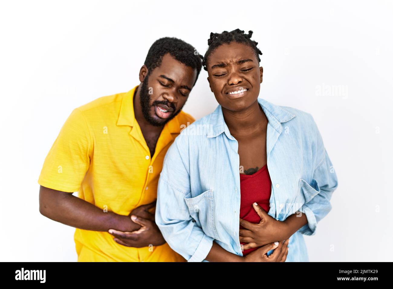 Giovane coppia afroamericana che indossa abiti casual con mano sullo stomaco perché nausea, malattia dolorosa sensazione di malessere. Mal concetto. Foto Stock