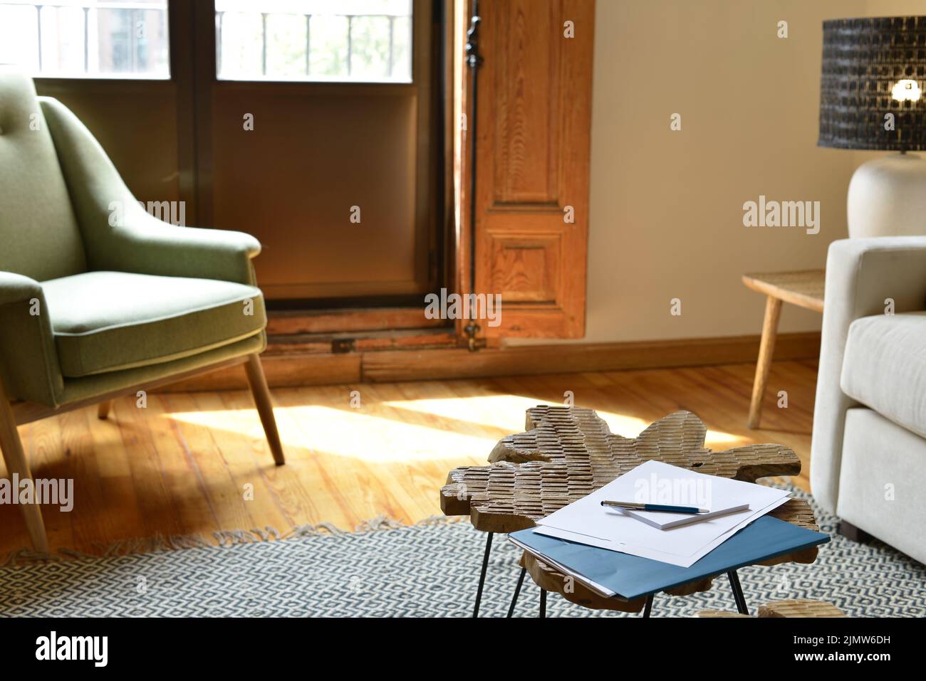 Angolo soggiorno con pavimenti in legno di pino, tavolo laterale in legno e balcone con grandi finestre Foto Stock