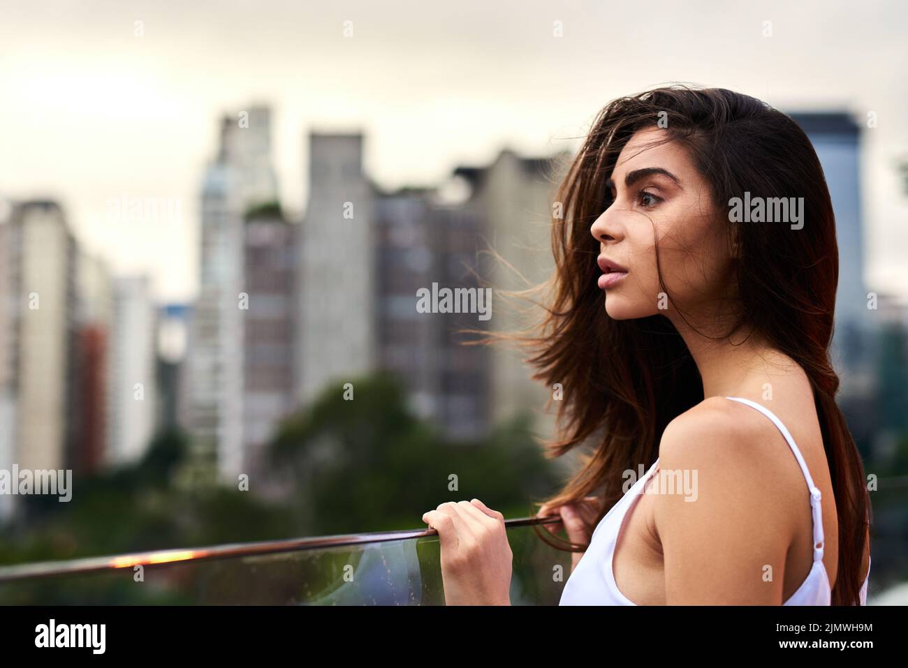 Bellezza naturale. Una giovane donna attraente in piedi su un balcone all'aperto durante il giorno. Foto Stock