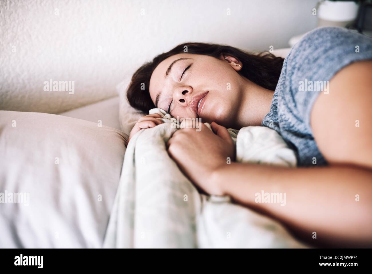 Un sonno abbastanza è una forma di cura di sé, una giovane donna attraente che dorme sul suo letto la mattina a casa. Foto Stock