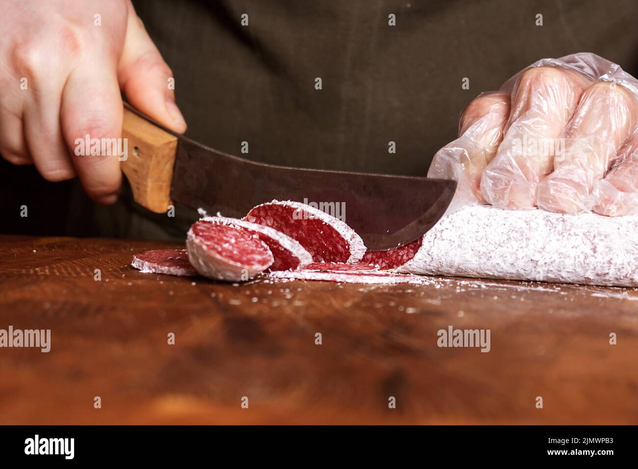 Donna di vendita fette salame salsiccia su tavola di legno. Foto Stock