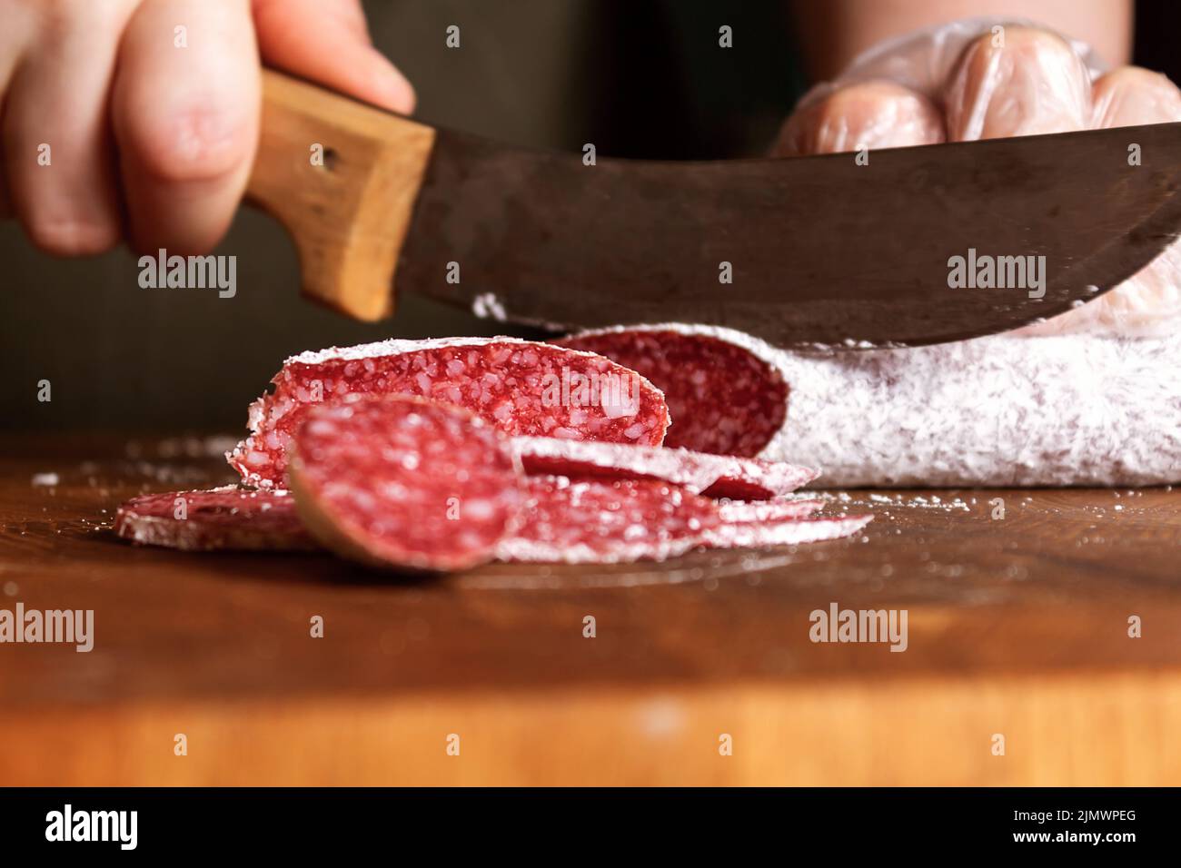 Donna di vendita fette salame salsiccia su tavola di legno. Foto Stock