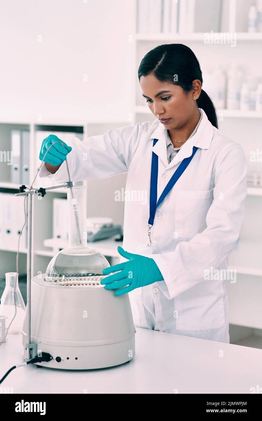 Shes determinato per ottenere i risultati. Una giovane scienziata femminile attraente che lavora con una centrifuga ed un pallone conico in un laboratorio. Foto Stock