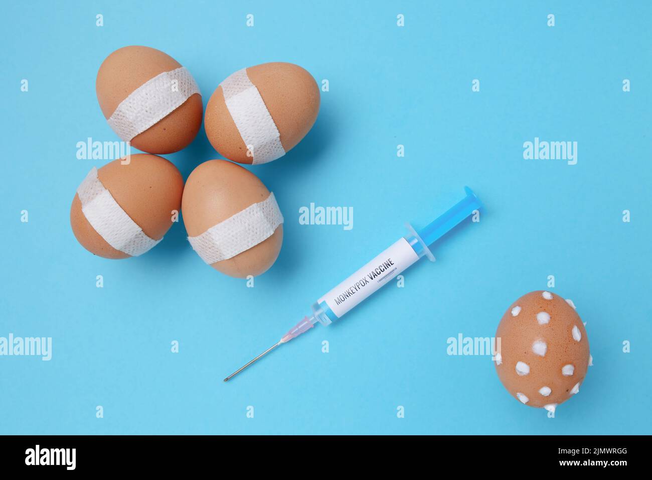 flatlay con siringa di vaccino di scimmietta, uova vaccinate con cerotto medico e uova con sintomi di scimmietta su sfondo blu. Foto Stock